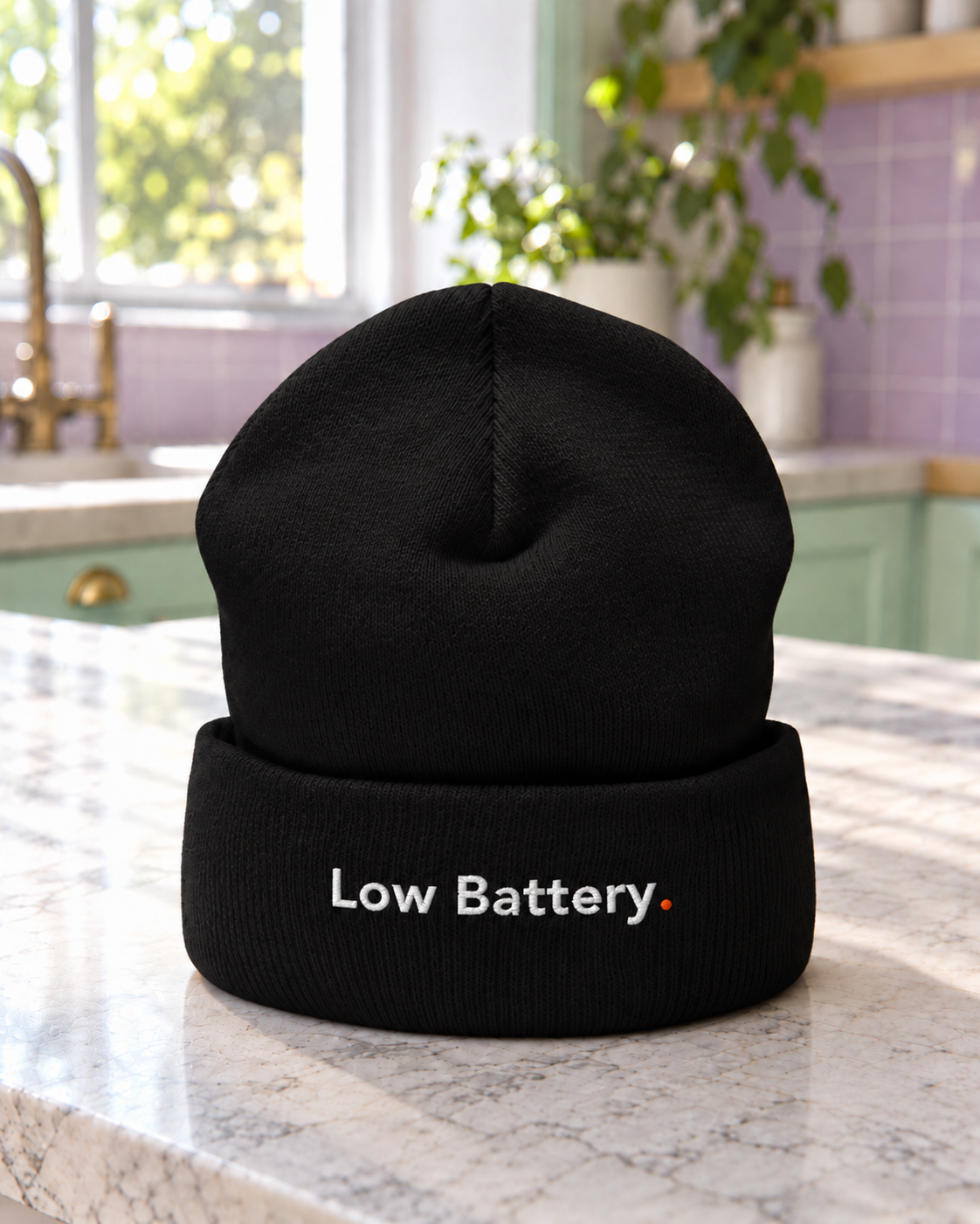 Black Low Battery. embroidered cuffed beanie on a pastel kitchen counter