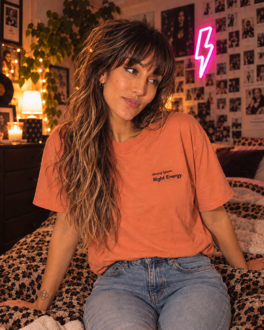 Woman wearing the Wrong Spoon. Right Energy. embroidered Pastel Pop tee in Terracotta, sitting on a bed