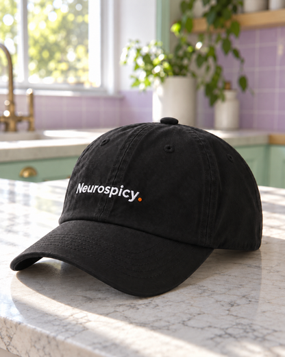 Black Neurospicy. embroidered cap on a pastel kitchen counter, three-quarter view