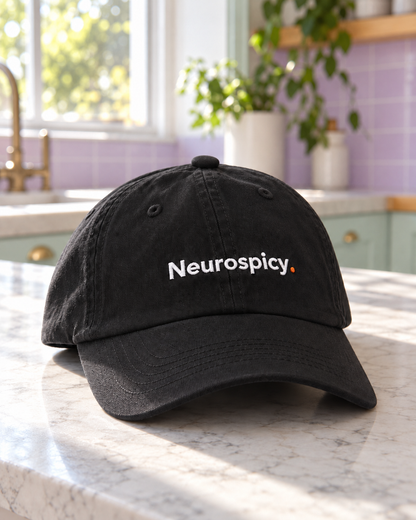 Black Neurospicy. embroidered cap on a pastel kitchen counter, angled view