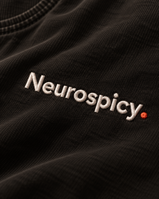 Close-up of the Neurospicy. embroidery on Washed Black fabric